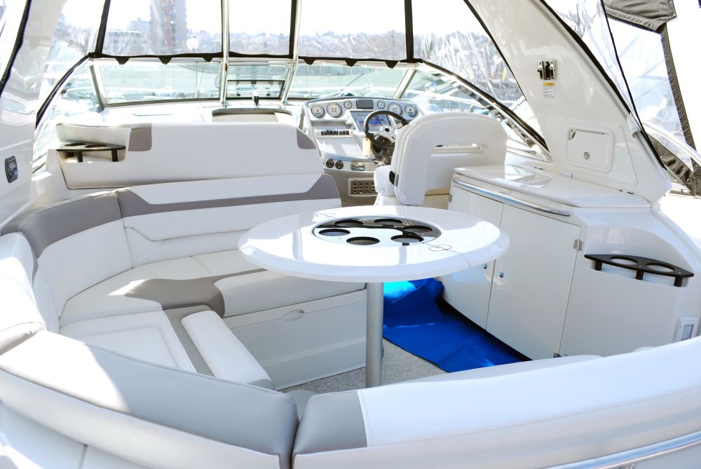 Luxurious boat interior after professional detailing, featuring clean and polished seating, table, and helm area for a pristine finish.